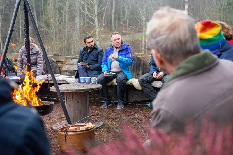 Bål i forgrunn og politiker Tore Sandvik i bakgrunn