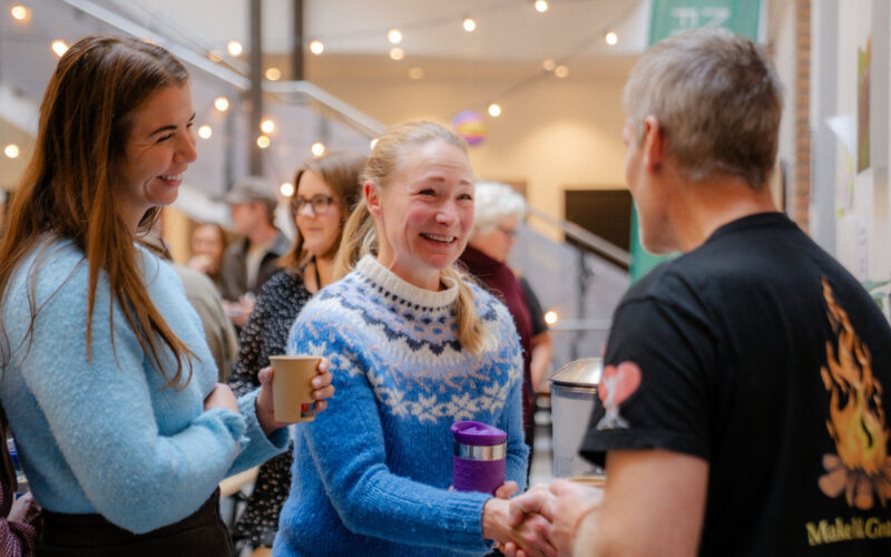Mennesker smiler og møter hverandre, mens de tar hverandre i hånda.