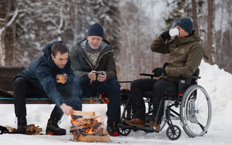 Tre menn sitter rundt bål. En mann er i rullestol. Illustrasjonsbilder for Hele Norge båler i Friluftslivets år.