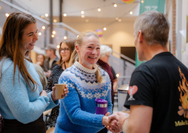 Mennesker smiler og møter hverandre, mens de tar hverandre i hånda.