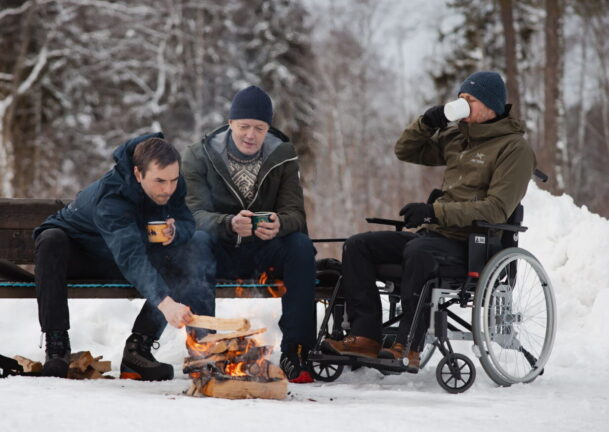 Tre menn sitter rundt bål. En mann er i rullestol. Illustrasjonsbilder for Hele Norge båler i Friluftslivets år.