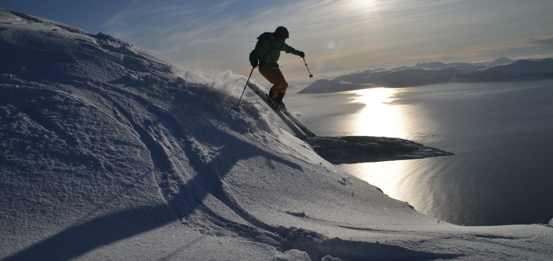 Mann på ski med sola i bakgrunnen