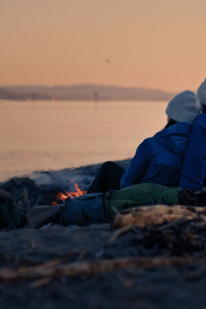 Et par sitter og ser ut over fjorden etter solnedgang.